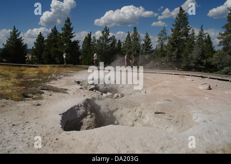 Blauer Himmel weiße Wolken Blick auf touristische Promenade Bäume, graue Sinter Lüftungsschlitze rot Spouter Fumarole, Lower Geyser Basin, Yellowstone Stockfoto