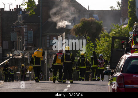 London, UK. 1. Juli 2013. Feuerwehrleute zusehen, wie Rauch aus der Werkstatt noch gießt, nachdem sie das Feuer gedämpft und gekühlt Gasflaschen auf dem Rad & Reifen Co Kensal Green hatte. Bildnachweis: Paul Davey/Alamy Live-Nachrichten Stockfoto