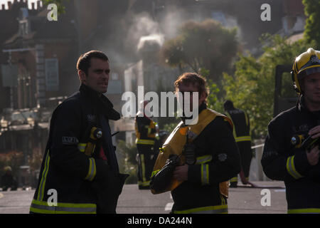 London, UK. 1. Juli 2013. Feuerwehr beginnt mit Rauch aus einer Öffnung noch gießen zu deren Betrieb nach einem Brand auf dem Rad & Reifen Co Kensal Green downscale. Bildnachweis: Paul Davey/Alamy Live-Nachrichten Stockfoto