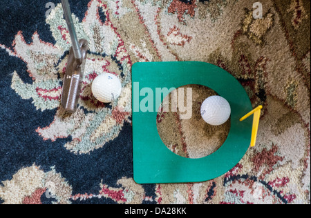 Ein Hallenbad Praxis Golf Putting Cup mit zwei Golfbälle, während ein Putter die Kugel auf einem Teppich Adressen. USA Stockfoto