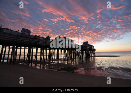 Rote Wolken über Kopf als Sonne steigt Strand mit Promenade entlang auf Stelzen im Süden Harbor, Maine. Stockfoto