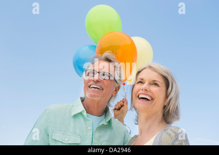 Älteres Paar mit Haufen Luftballons gegen klarer Himmel Stockfoto