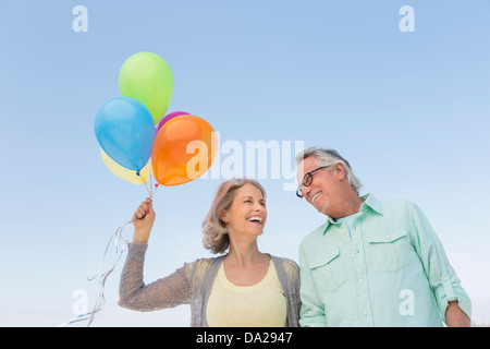 Älteres Paar mit Haufen Luftballons gegen klarer Himmel Stockfoto