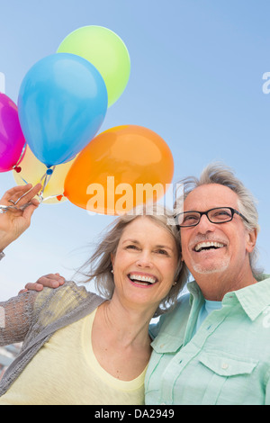 Älteres Paar mit Haufen Luftballons gegen klarer Himmel Stockfoto