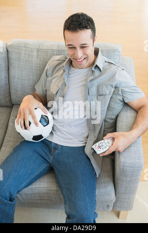 Junger Mann beobachten Fußballspiel im Fernsehen Stockfoto