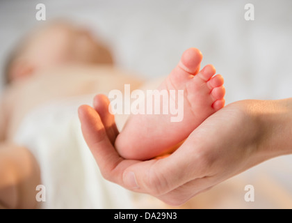 Nahaufnahme von Mutters Hand mit winzigen Fuß Baby girl (6-11 Monate) Stockfoto