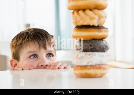 Porträt eines jungen (4-5) Blick auf gestapelten donuts Stockfoto