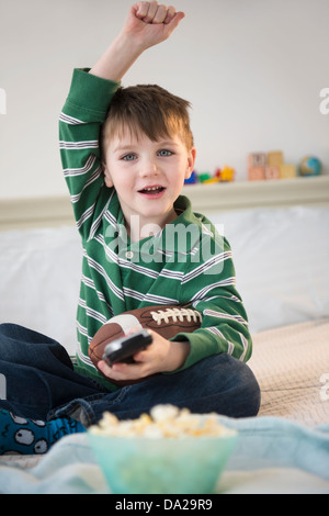 Porträt der fröhliche junge (4-5) sitzt auf dem Bett, hält Fußball Stockfoto