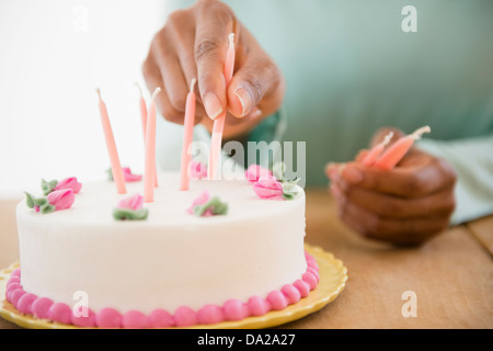Nahaufnahme von Frauenhand putting Kerzen auf der Geburtstagstorte Stockfoto