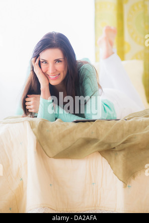 Porträt der Frau liegend auf dem Bett mit Kopf in Händen Stockfoto