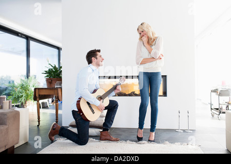 Mann spielt Gitarre vor Frau Stockfoto