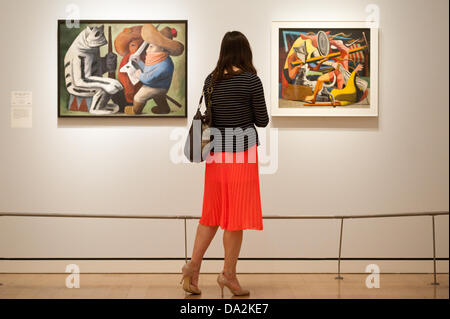 London, UK - 2. Juli 2013: ein Besucher steht neben einer Arbeit von Josè Chavez Morado mit dem Titel "Carnaval de Huejotzingo 1939' (L) in der Ausstellung" Mexiko: A Revolution in der Kunst, 1910 – 1940', an der königlichen Akademie der Künste am 6. Juli öffnet. Die Show bietet über 120 Gemälden und Fotografien und untersucht den intensiven künstlerischen Schaffens, das zu Beginn des 20. Jahrhunderts in Mexiko stattfand. Bildnachweis: Piero Cruciatti/Alamy Live-Nachrichten Stockfoto