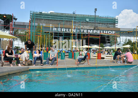 Besucher sitzen außerhalb der Modemagazins-Messe «& Brot» infront auf dem ehemaligen Flughafen Tempelhof in Berlin auf einen Pool, Deutschland, 2. Juli 2013. Die Präsentationen der Kollektionen für Frühjahr/Sommer 2014 statt vom 02 bis 4. Juli 2013. Foto: Marc Tirl/Dpa +++(c) Dpa - Bildfunk +++ Stockfoto