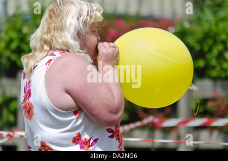 Frau bläst einen gelben Ballon Stockfoto