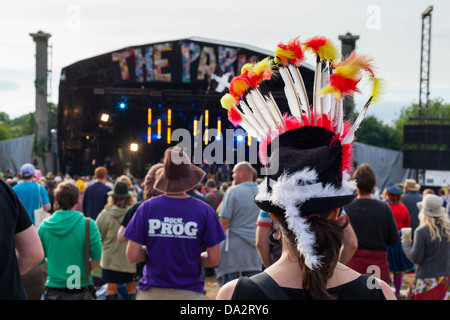 GLASTONBURY FESTIVAL, UNITED KINGDOM - 30. Juni 2013: Rückansicht einer Frau einen bunt gefiederten Hut im Park Stadium Stockfoto