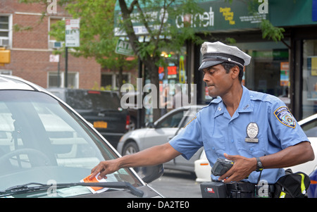 Ein Verkehrspolizist von New York City bietet ein Ticket zu einem geparkten Fahrzeug für eine abgelaufene Meter. In Jackson Heights, Queens, New York Stockfoto