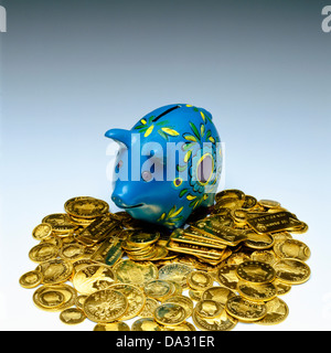 Blaues Sparschwein mit Goldmünzen Stockfoto