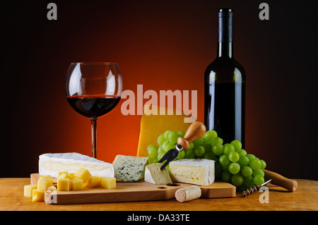 Stillleben mit Glas und Flasche Rotwein, Käse und Trauben Stockfoto