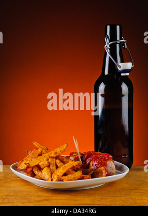 Curry Wurst mit Pommes Frites und Flasche Bier Stockfoto