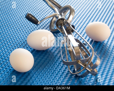 Drei Eiern mit Vintage Rotary Hand Schlägel auf blauem Hintergrund Stockfoto