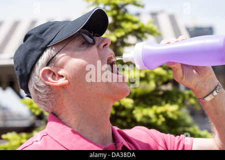 Reifer Mann trinkt aus der Flasche Wasser Stockfoto