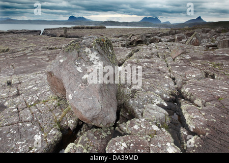 Felsen bedeckt in Flechten unter einem dramatischen Himmel am Ufer des Enard Bay, Sutherland, Nord-West-Schottland Stockfoto