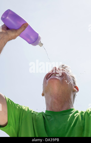 Ein älterer Mann, der Wasser über sein Gesicht schüttet, um die Hitzeerschöpfung zu lindern, USA Stockfoto