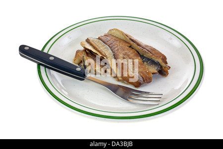 Eine Portion geräucherte Heringsfilets auf dem grün gestreiften Teller mit Gabel. Stockfoto