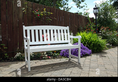 eine weiße Holzbank in einem Garten Stockfoto