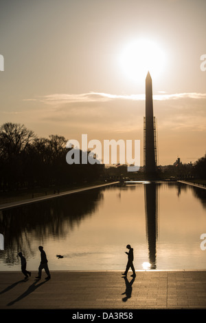 Die Morgensonne Silhouetten das Washington Monument auf dem Reflecting Pool in Washington DC. Gerüst umgibt den Denkmal Teil des Weges auf. Stockfoto