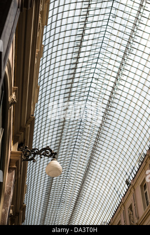 BRÜSSEL, Belgien — das elegante Glaskuppeldach der Galeries Royales Saint-Hubert beleuchtet die historische Einkaufspassage in Brüssels Unterstadt. Diese 1847 eröffnete europäische überdachte Einkaufsstraße umfasst drei miteinander verbundene Galerien mit Luxusläden und Cafés. Stockfoto