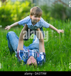 Spielen auf der Wiese mit seinem kleinen Sohn Vater Stockfoto