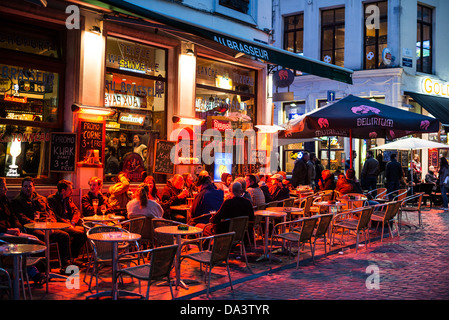 Gäste essen und trinken auf Sitzgelegenheiten im Freien vor einem Pub / bar in der Altstadt von Brüssel, in der Nacht. Stockfoto