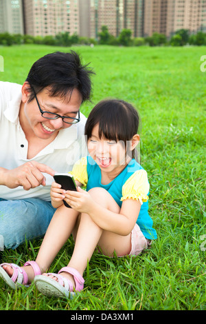 glücklicher Vater und Mädchen beobachten das Smartphone Stockfoto