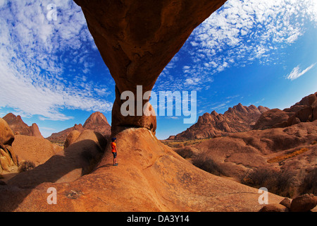 Junge unter natürlichen Felsen arch Spitzkoppe (links) und Pondok Berge in Ferne (rechts), Namibia, Afrika Stockfoto