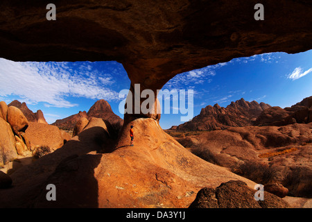 Junge unter natürlichen Felsen arch Spitzkoppe (links) und Pondok Berge in Ferne (rechts), Namibia, Afrika Stockfoto