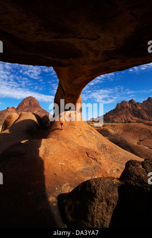 Junge unter natürlichen Felsen arch Spitzkoppe (links) und Pondok Berge in Ferne (rechts), Namibia, Afrika Stockfoto