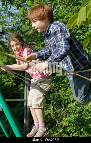 junges Mädchen und Jungen gemeinsam auf Schaukel Stockfoto