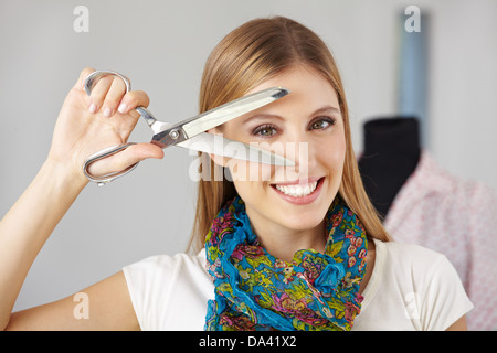 Attraktive Frau lächelnd mit einer Schere vor ihr Gesicht Stockfoto