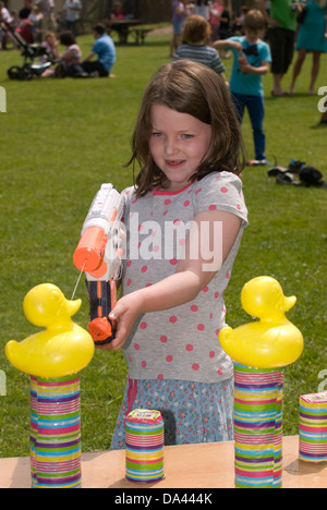 7-Jähriges Mädchen im Summer Fete mit Wasserpistole Kunststoff Enten, Blatt, Hampshire zu sprizen, UK. Stockfoto