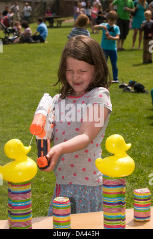 7-Jähriges Mädchen im Summer Fete mit Wasserpistole Kunststoff Enten, Blatt, Hampshire zu sprizen, UK. Stockfoto