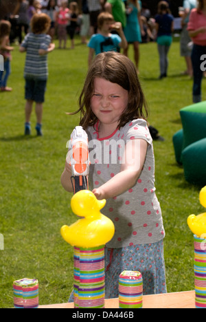 7-Jähriges Mädchen im Summer Fete mit Wasserpistole Kunststoff Enten, Blatt, Hampshire zu sprizen, UK. Stockfoto