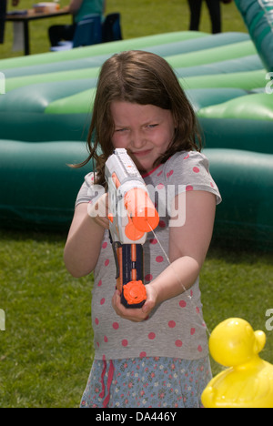 7-Jähriges Mädchen im Summer Fete mit Wasserpistole Kunststoff Enten, Blatt, Hampshire zu sprizen, UK. Stockfoto