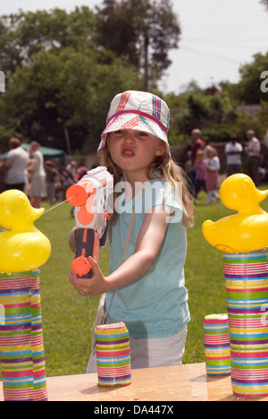 7-Jähriges Mädchen im Summer Fete mit Wasserpistole Kunststoff Enten, Blatt, Hampshire zu sprizen, UK. Stockfoto