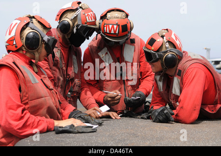 US Marine Luftfahrt Ordnance Männer Nachbesprechung nach dem Laden von Flugzeugen Waffen im Flugbetrieb an Bord des Flugzeugträgers USS Nimitz 19. Juni 2013 in den Golf von Oman. Stockfoto