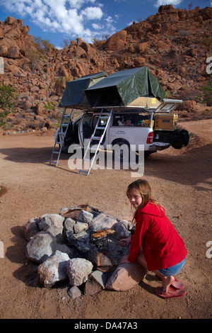 Mädchen Kochen Toast auf einem Lagerfeuer am Campingplatz am Mowani Mountain Camp in der Nähe von Twyfelfontein, Damaraland, Namibia, Afrika Stockfoto