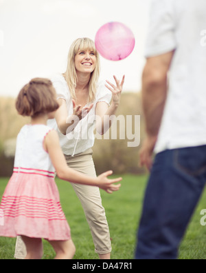 Vater Mutter und Tochter wirft Ball zueinander im park Stockfoto