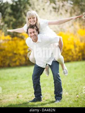 Mann Huckepack Frau im park Stockfoto