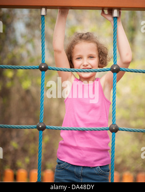 Halblanger Schuss des jungen Mädchens auf Kletternetz Stockfoto