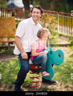 Vater und Tochter auf Spielplatz Frühling Reiter Stockfoto